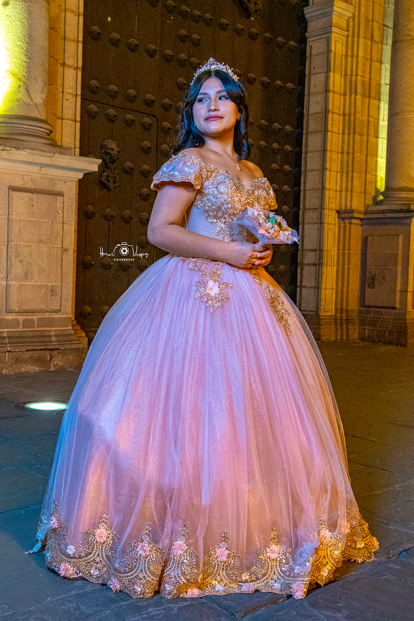 Anto con vestido rosado frente a una fachada iluminada de noche