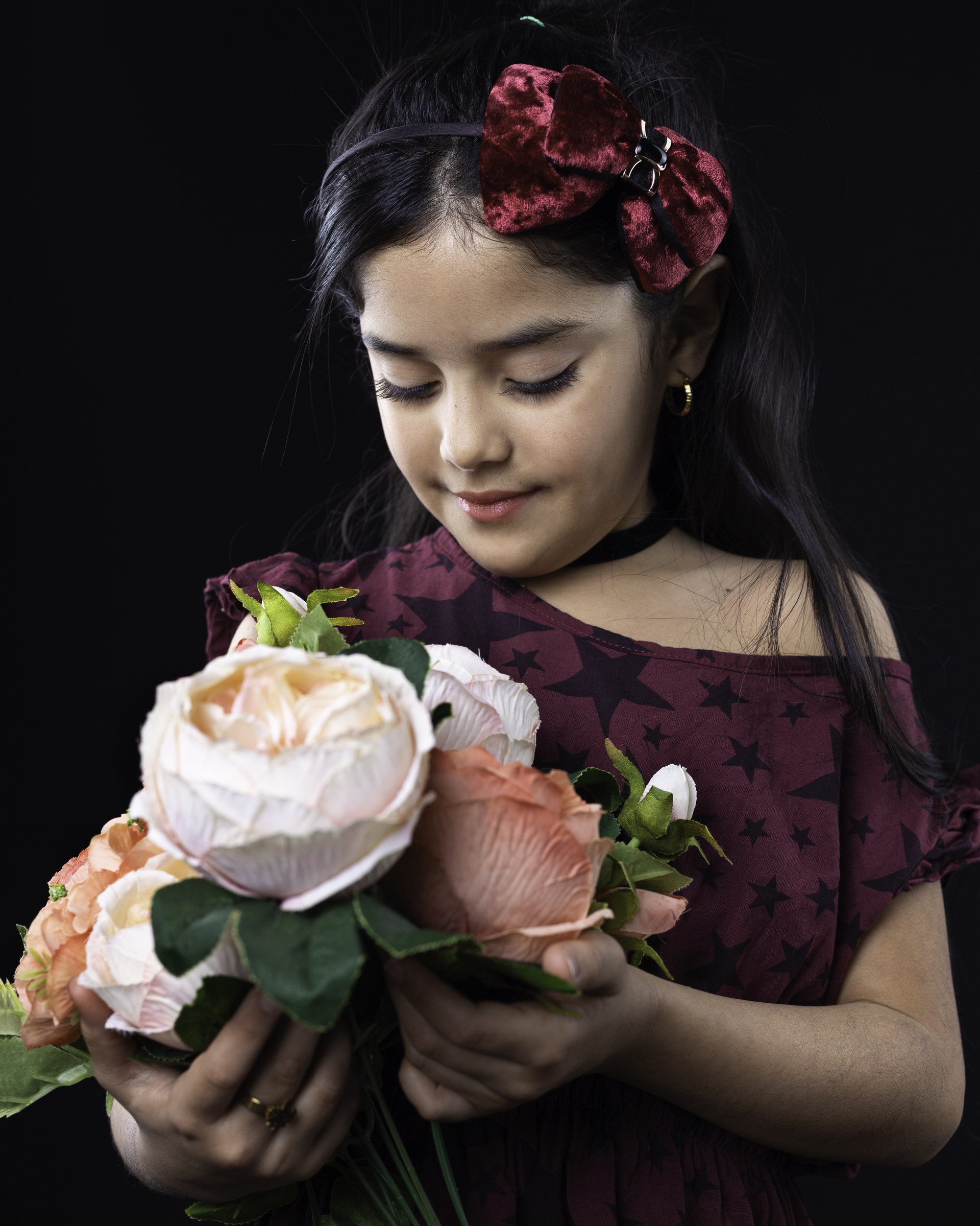 Nicol con un ramo de flores iluminado sobre fondo oscuro