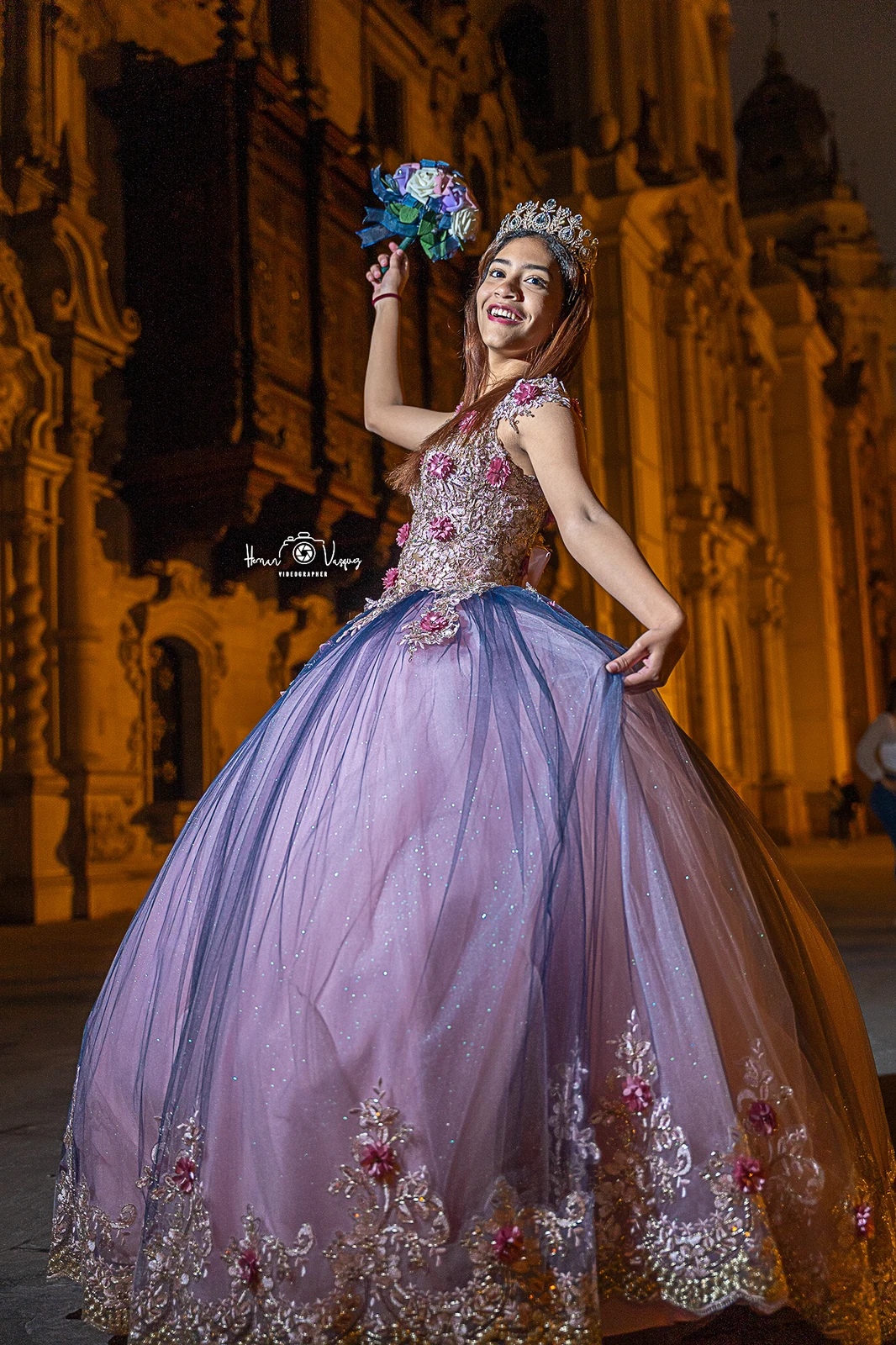 Quinceañera posando de noche frente a una arquitectura iluminada