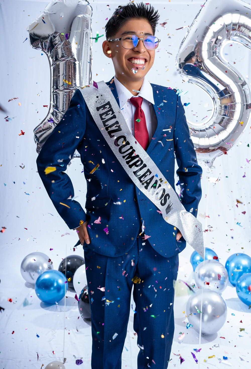 Santi con traje azul y banda de cumpleaños entre confeti